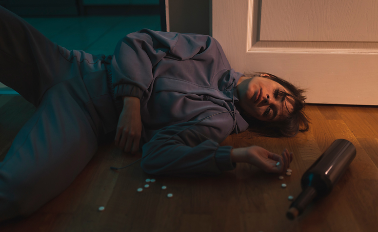Young female addict collapsed on floor after drug and alcohol consumption