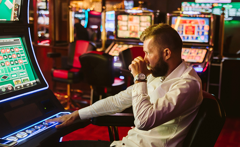 Addicted gambler, drinking and playing on the slot machines