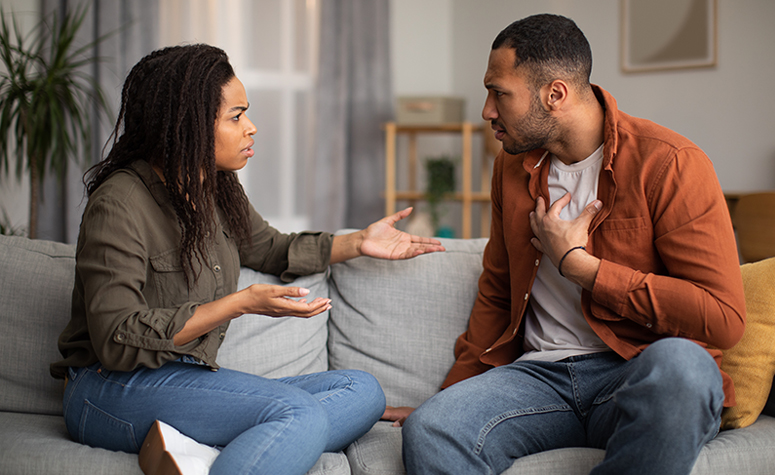 Codependent couple sat on sofa in an argument