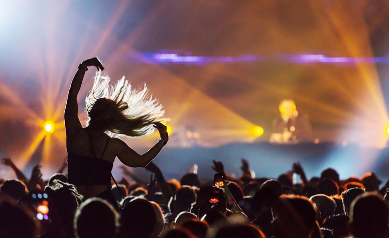 Girl at concert experiencing a euphoric moment with arms in the air