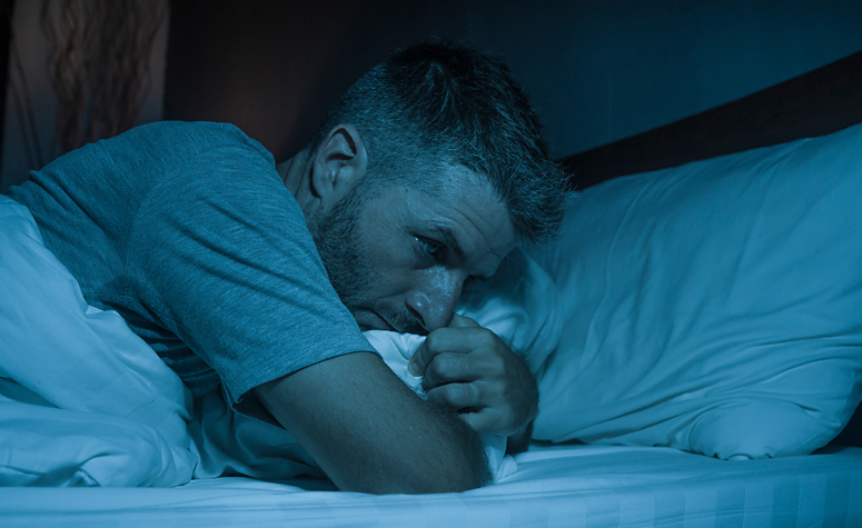 Man lying in bed suffering from depression and insomnia