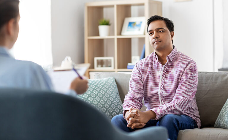 Man in therapy treatment discussing his work addiction with therapist