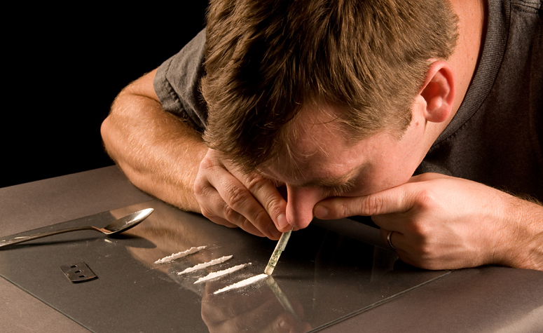 Man snorting drugs at table