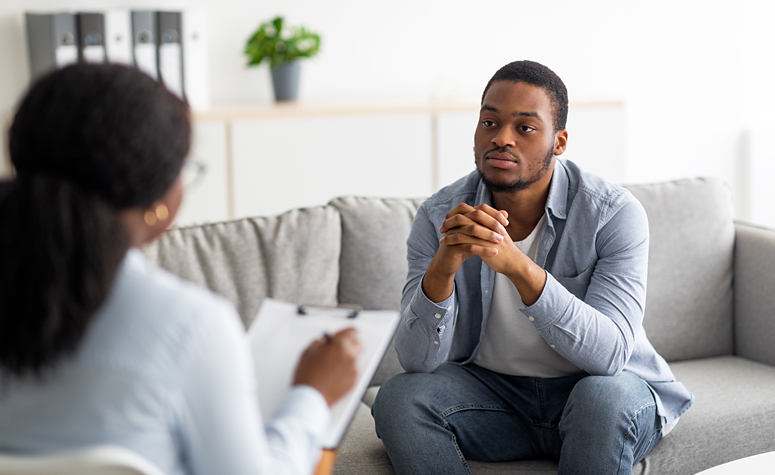 Man suffering with alcoholism meets with psychologist in therapy