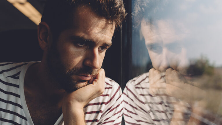 Man with suffering with anxiety disorder staring through the window