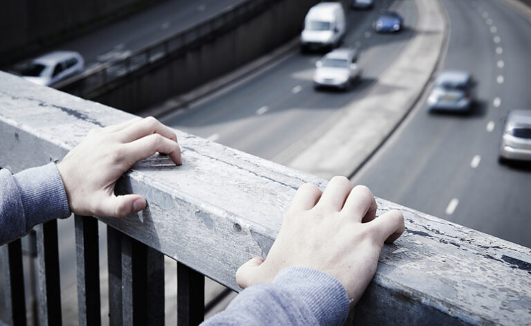 Depressed man stood on road bridge with suicidal thoughts
