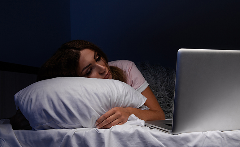 Woman addicted to the internet, laid in bed, falling asleep surfing on her laptop