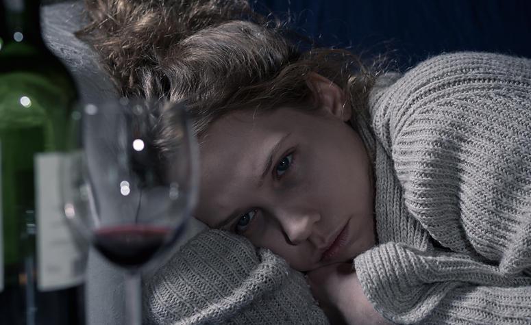 Woman depressed looking at glass of wine
