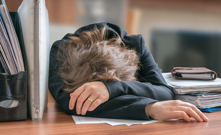 Woman suffering from work addiction tired and exhausted at desk