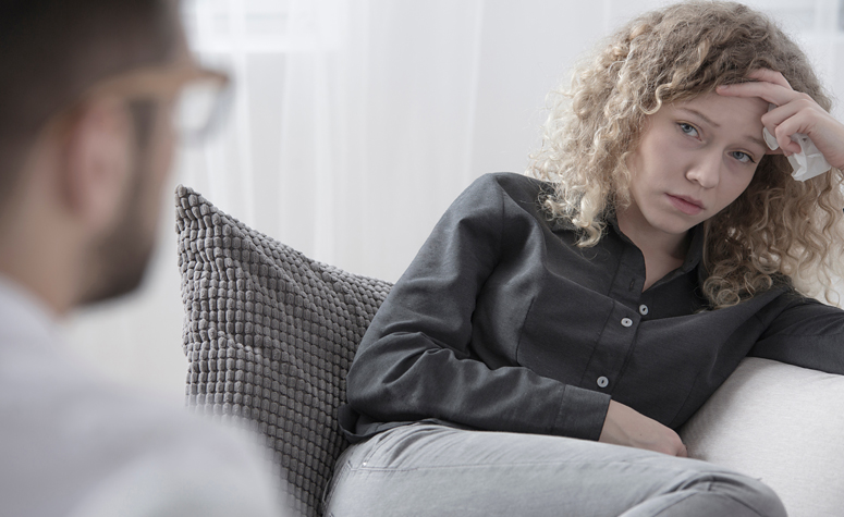 Woman sat in addiction therapy with psychologist at rehab center