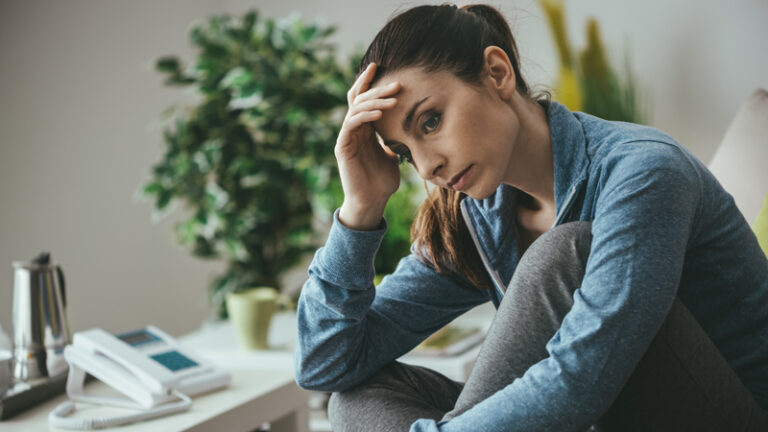 Woman sits at her desk struggling with anxiety disorder symptons