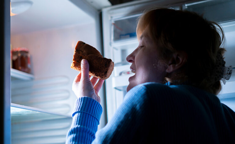 Woman sneaking food at night suffering from binge eating disorder