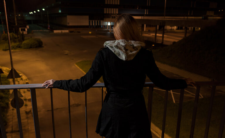 Woman suffering from depression stood next to railings having suicidal thoughts