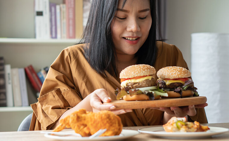 Woman suffering from binge eating disorder about to tuck into lots of junk food