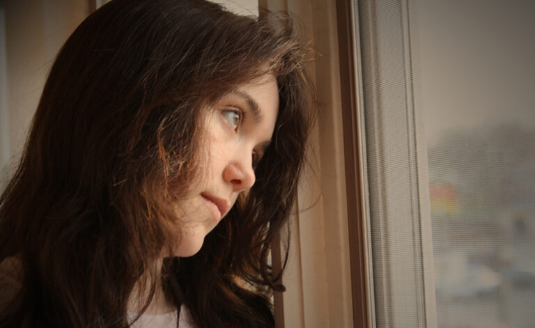 Women suffering with depression, feeling sad and looking gloomily out of the window