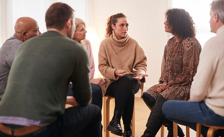 Group of people attending a 12 step recovery meeting following rehab treatment