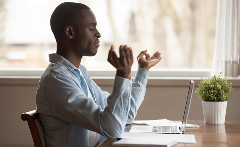 Man practising mindfulness meditation whilst taking a break from his work