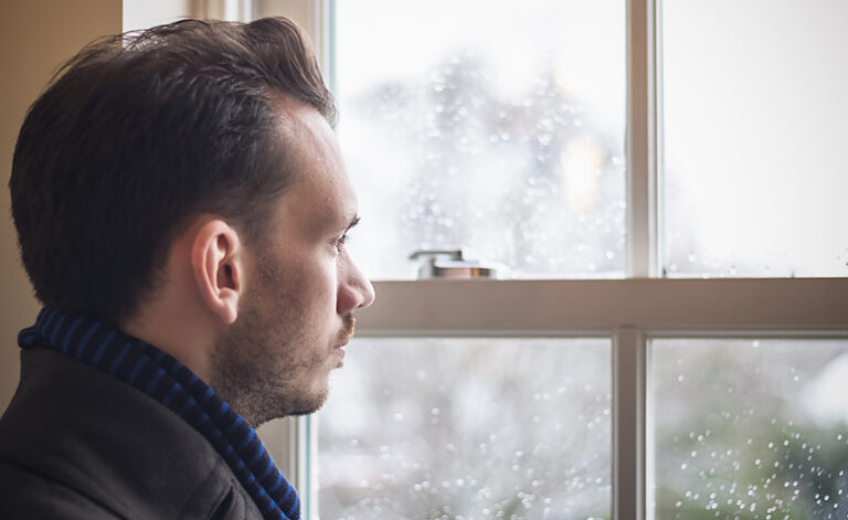 Man with seasonal affective disorder looking out of the window