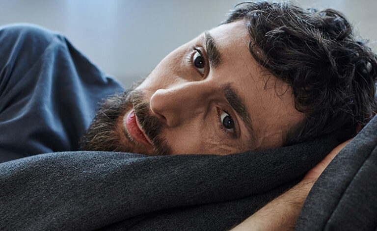 Man laid on the bed suffering with the symptoms of stress