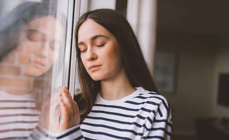 Woman stood at the window worrying about her health
