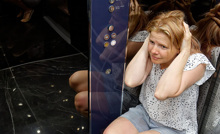 Woman in a lift experiencing an agoraphobia panic attack