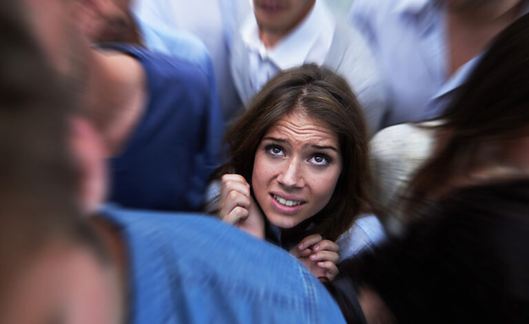 Women in a crowd of people struggling with symptoms of a panic attack
