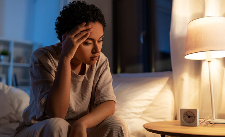 Woman sat up in bed struggling to sleep due to insomnia