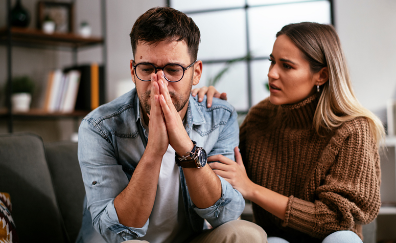 Man at home struggling with his mental health issues been comforted by a loved one
