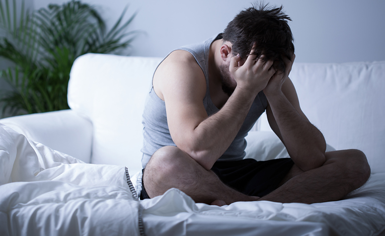 Man sat on sofa struggling with amphetamine withdrawal symptoms