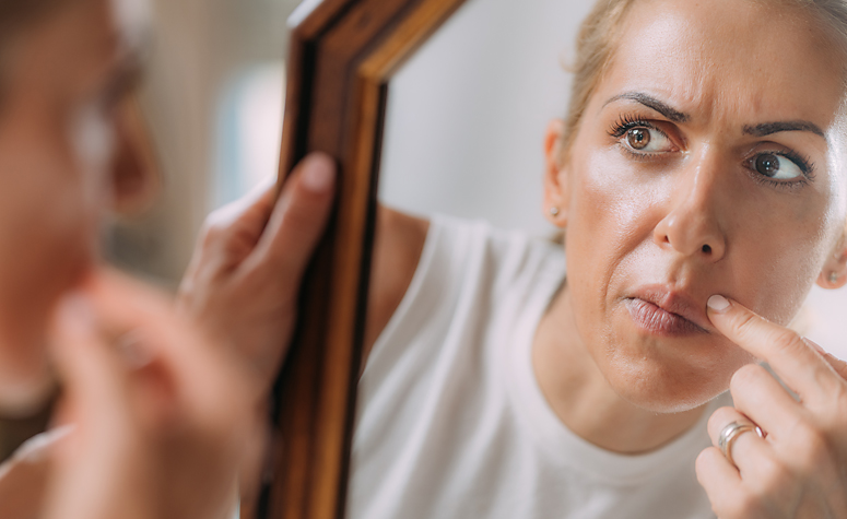 Woman with BDD obsessed with checking her face in the mirror
